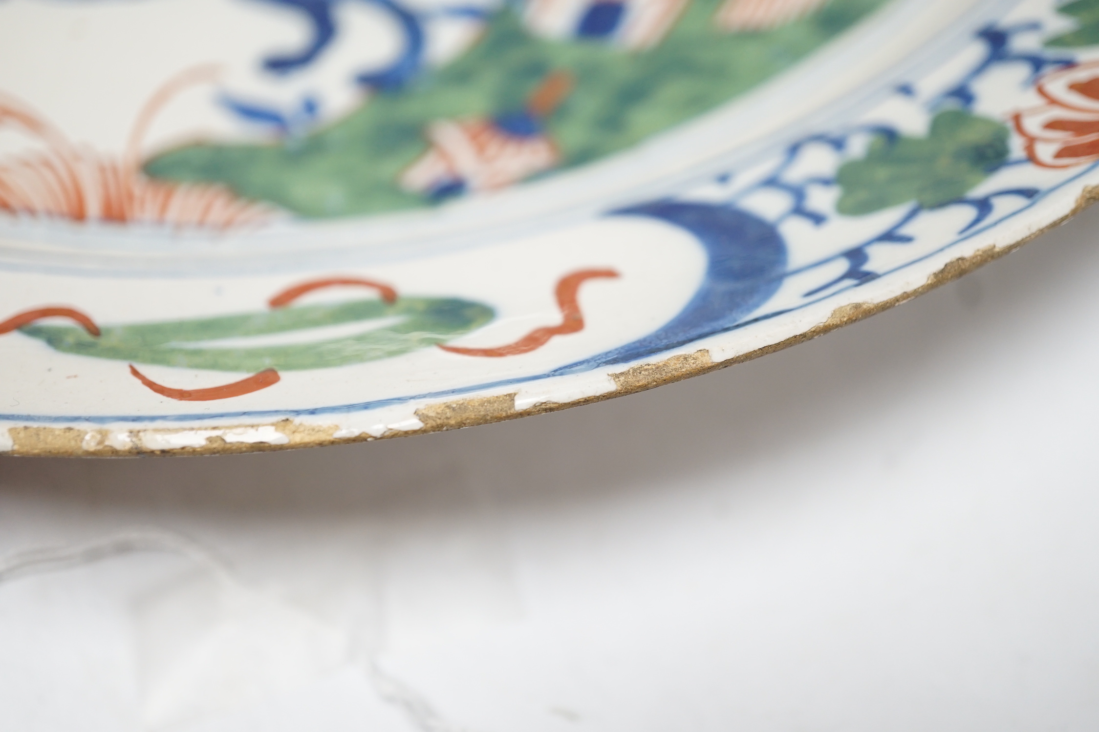 An 18th century Delft dish, the centre painted with a wolf, a bee and a pavilion, 35cm
